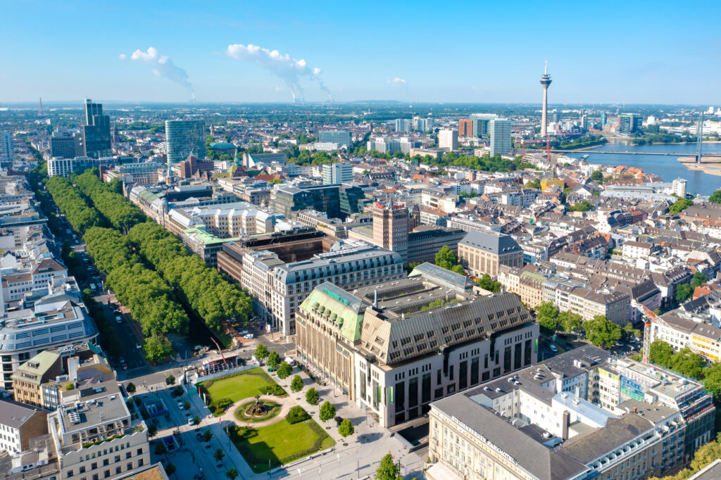 Abbildung von Düsseldorf mit Blick aus der Vogelperspektive auf die Königsallee, den Rheinturm sowie den Rhein mit Medienhafen im Hintergrund